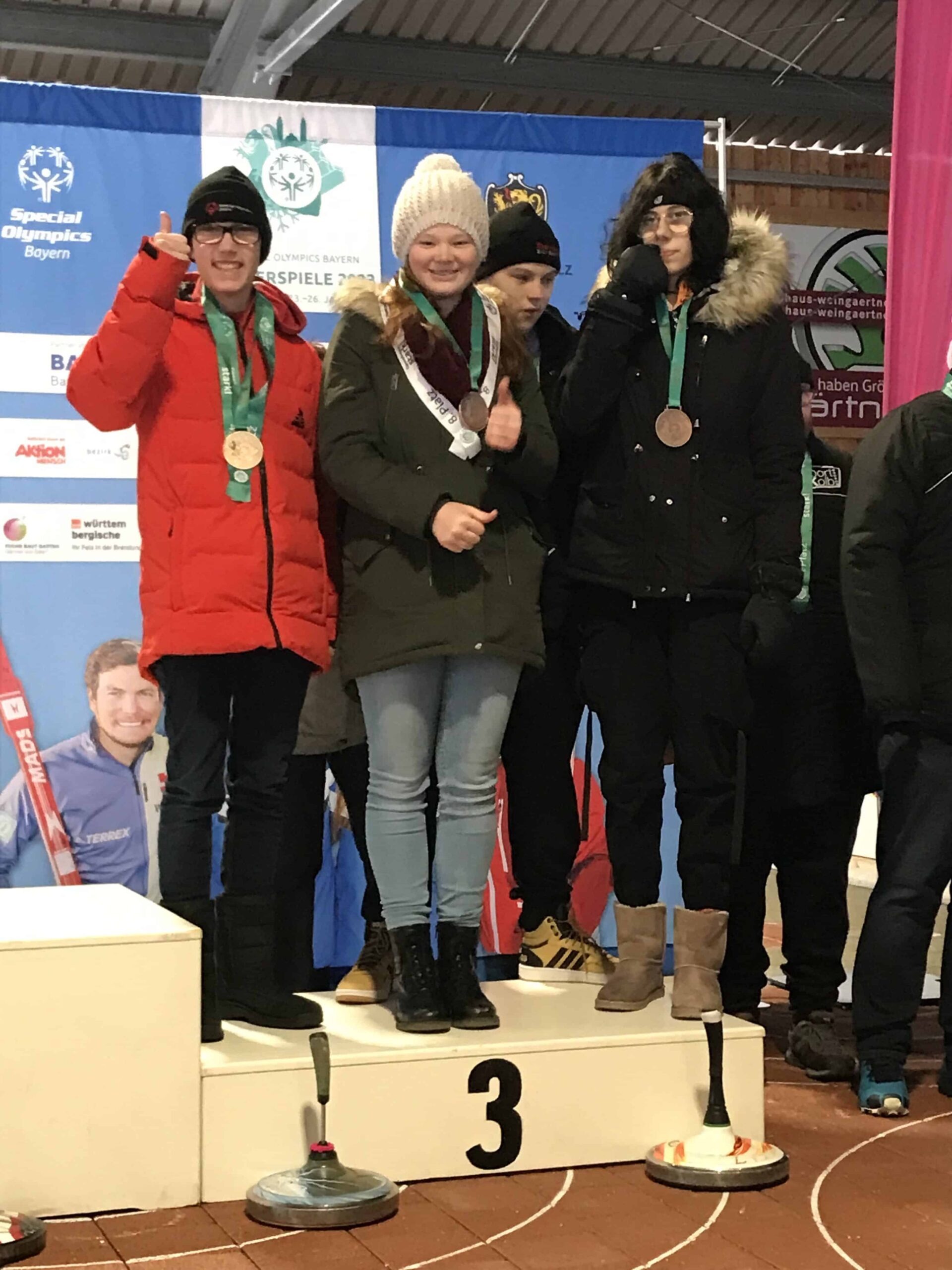 Junge Athleten mit Medaillen stehen auf einem Siegerpodest