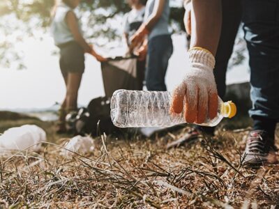 Eine Hand hebt gerade eine Plastikflasche auf.