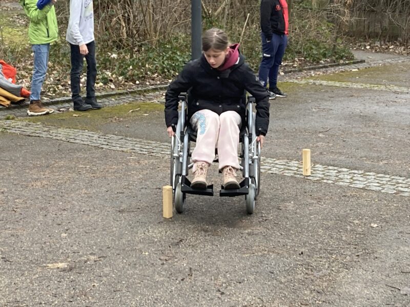 Auf dem Bild ist zu sehen, wie eine Schülerin durch die Holzstangen fährt.