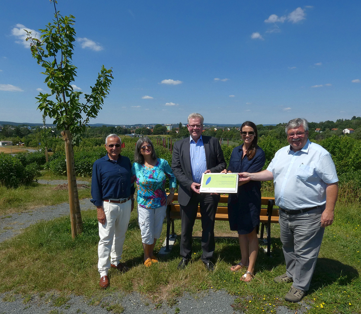 20230629 Spendenuebergabe Rotary Fünf Menschen stehen neben einem frisch gepflanzten Baum