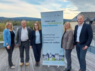 Die fünf Projektmitarbeitenden der Kooperation mit einem Roll-Up auf eine Dachterrasse