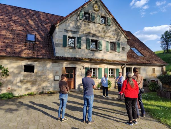 Teilnehmer und Archtekt stehn vor Sandsteingebäude