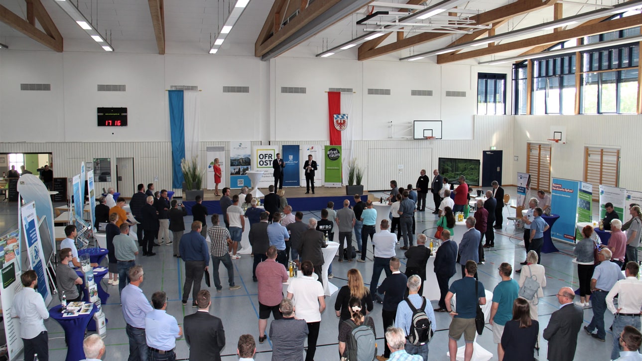 Zahlreiche Zuhörer stehen vor einem Podium in einer großen Halle. | Foto: Landratsamt Hof