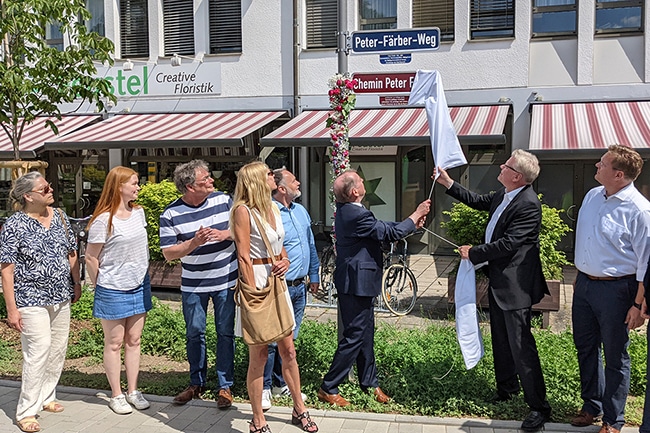 Mehrere Personen stehen vor einem Straßenschild, das soeben enthüllt wurde.