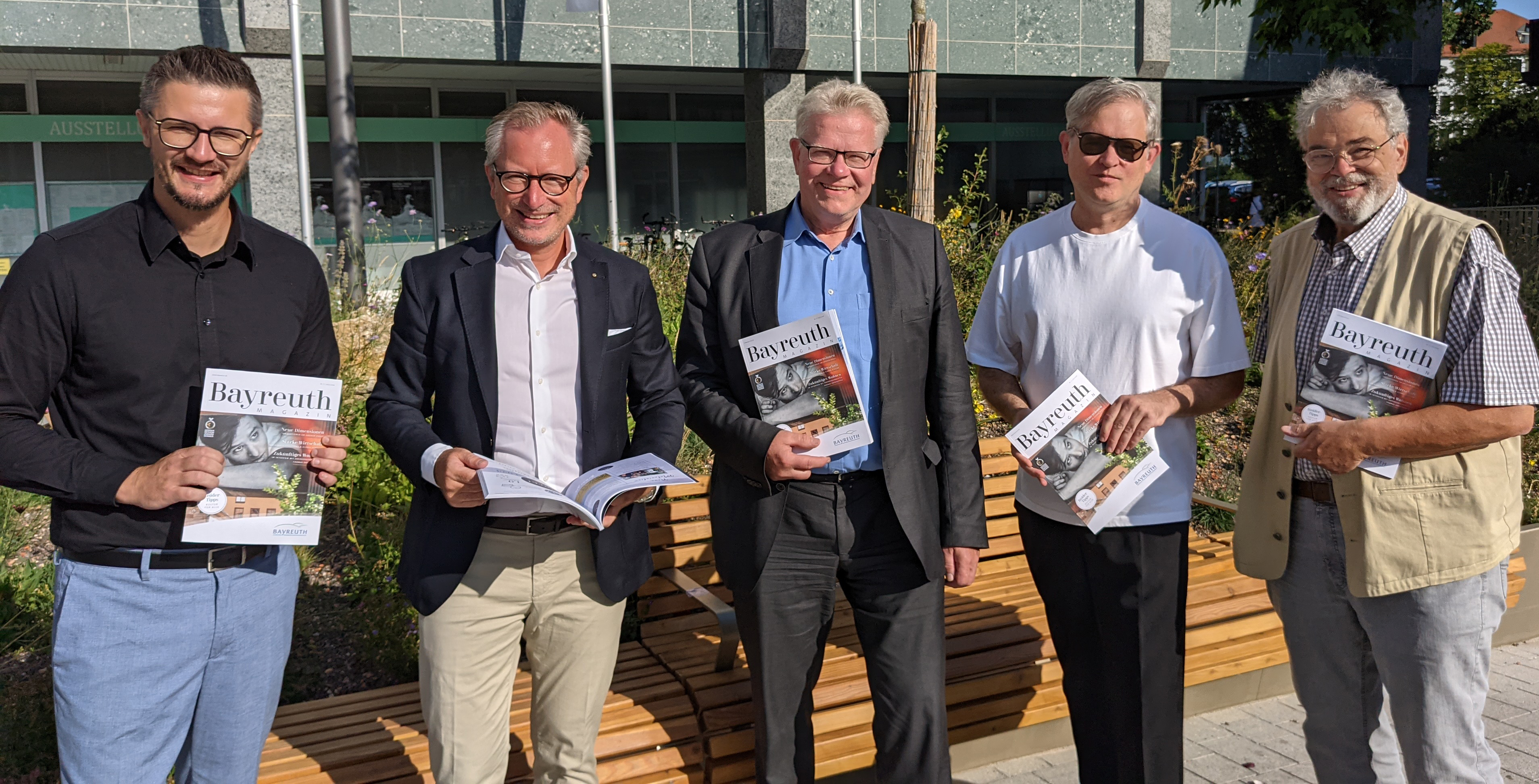 Fünf Männer stehen vor dem Rathaus und halten ein Bayreuth Magazin in ihren Händen.