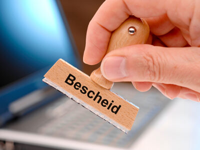 Bescheid auf Holzstempel in Hand
