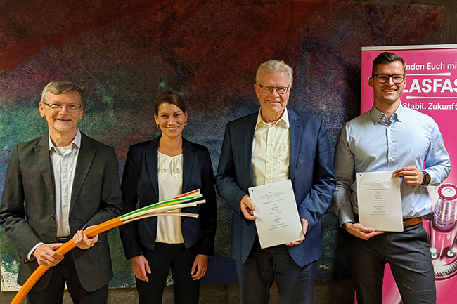 Fredy Schmidt, Jana Hofmann, OB Ebersberger und Richard Liedel stehen nebeneinander und halten die Verträge und ein Glasfaserkabel in der Hand