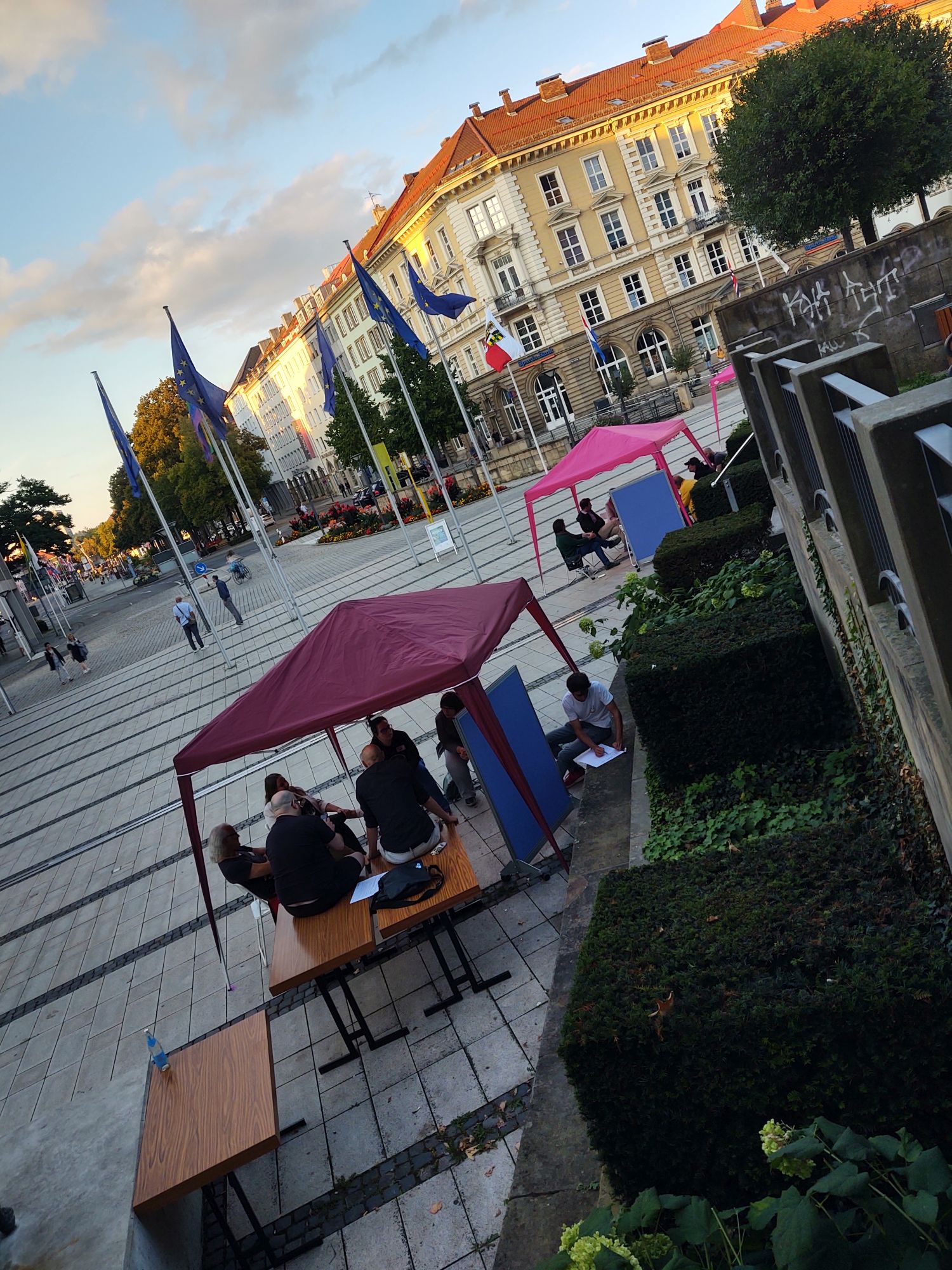 Arbeitsgruppen sitzen unter lila Pavillons am La Spezia Platz