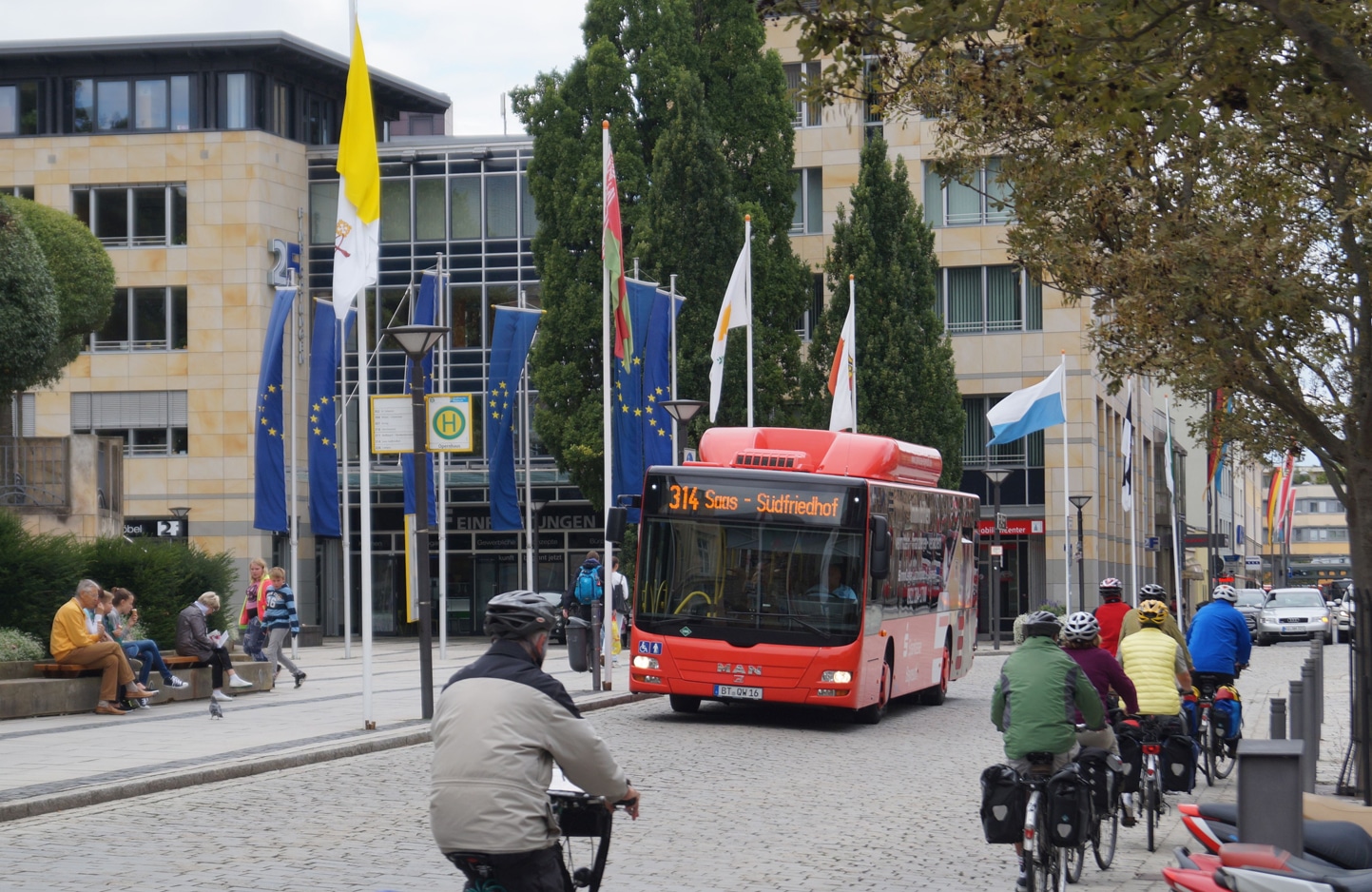 Fahrradfahrer begegnen einem Stadtbus auf einer belebten Straße.