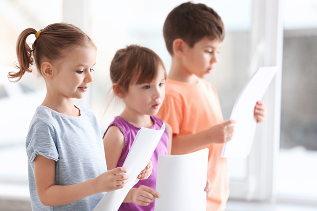 Drei singende Kinder mit Notenblättern in der Hand
