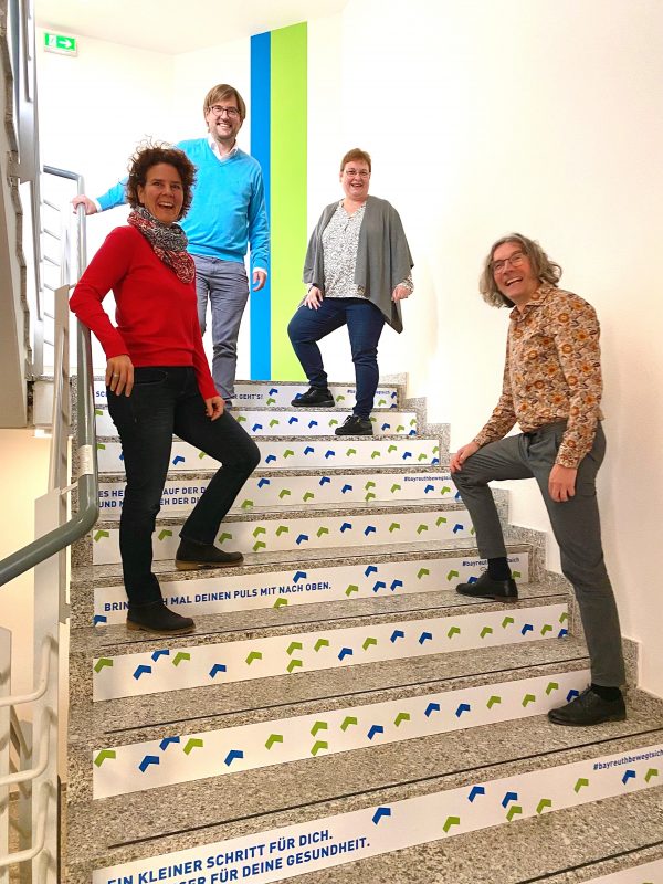 Vier Mitarbeiter stehen auf einer Treppe.
