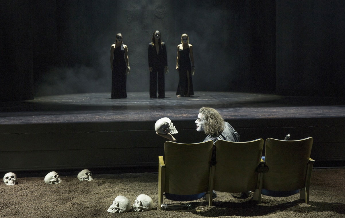 Drei Frauen stehen auf einer Theaterbühne. Im Vordergrund ein Mann auf einem Sofa. | Foto: H. Dietz