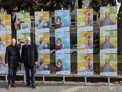 Landrat Wiedemann und Oberbürgermeister Ebersberger vor einer Plakatwand.