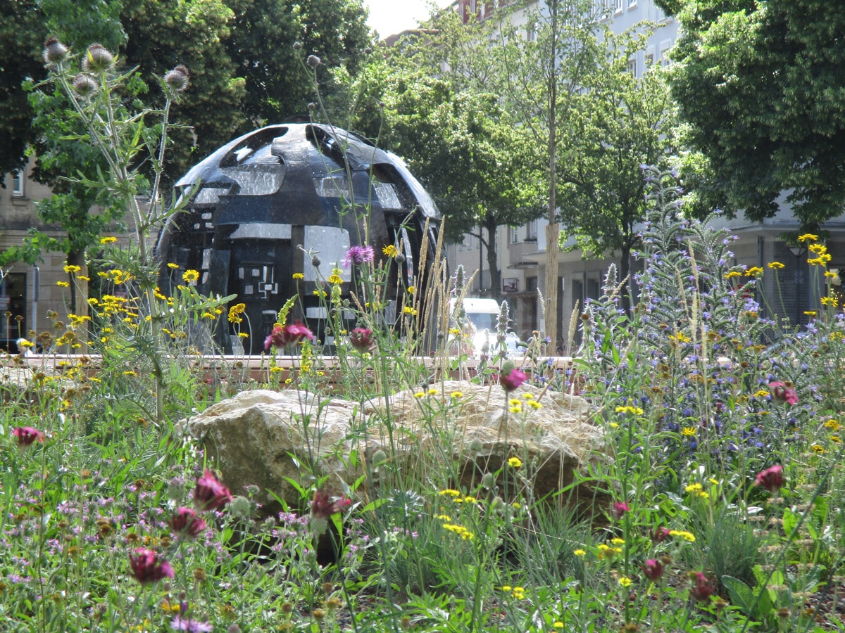 Kugelbrunnen mit Blumeninsel im Vordergrund