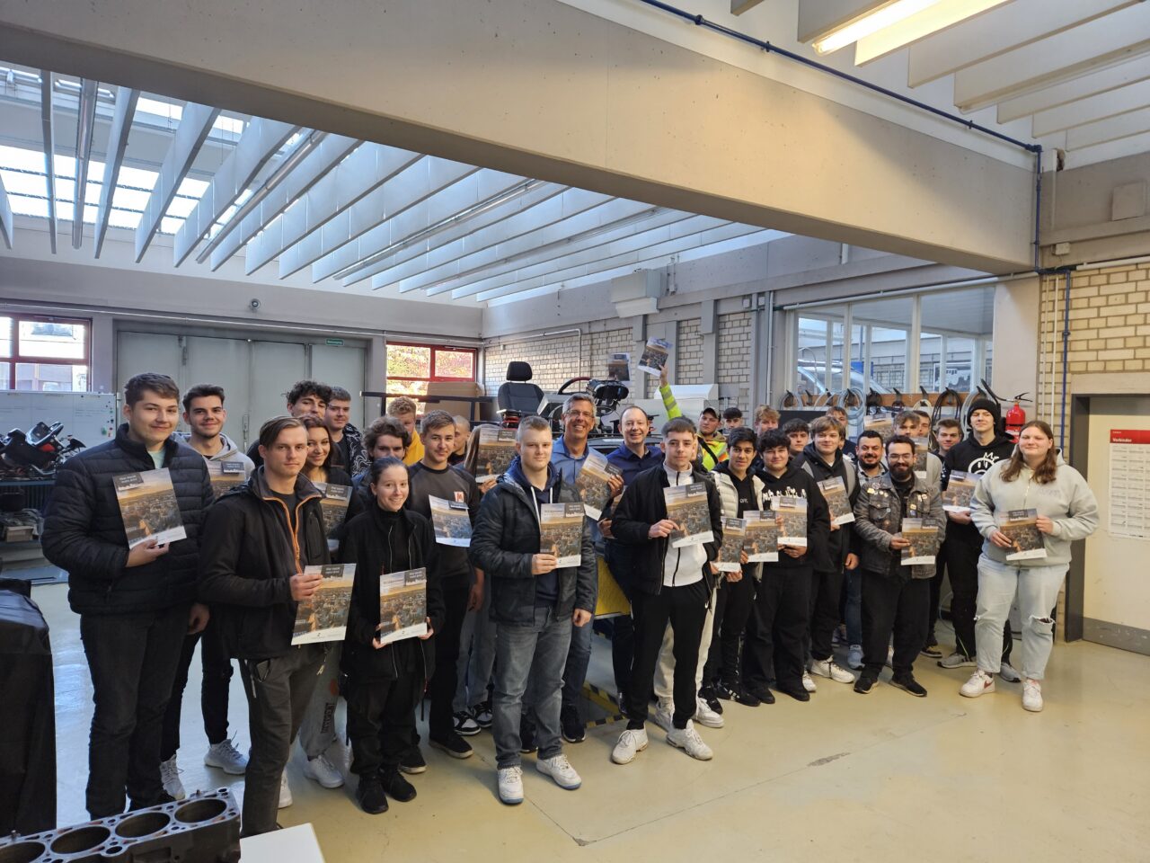 Fachkräftemanager Matthias Mörk und Schulleiter Thomas Hofmann mit einer Schulklasse bei der Überreichung der Willkommensgutscheine