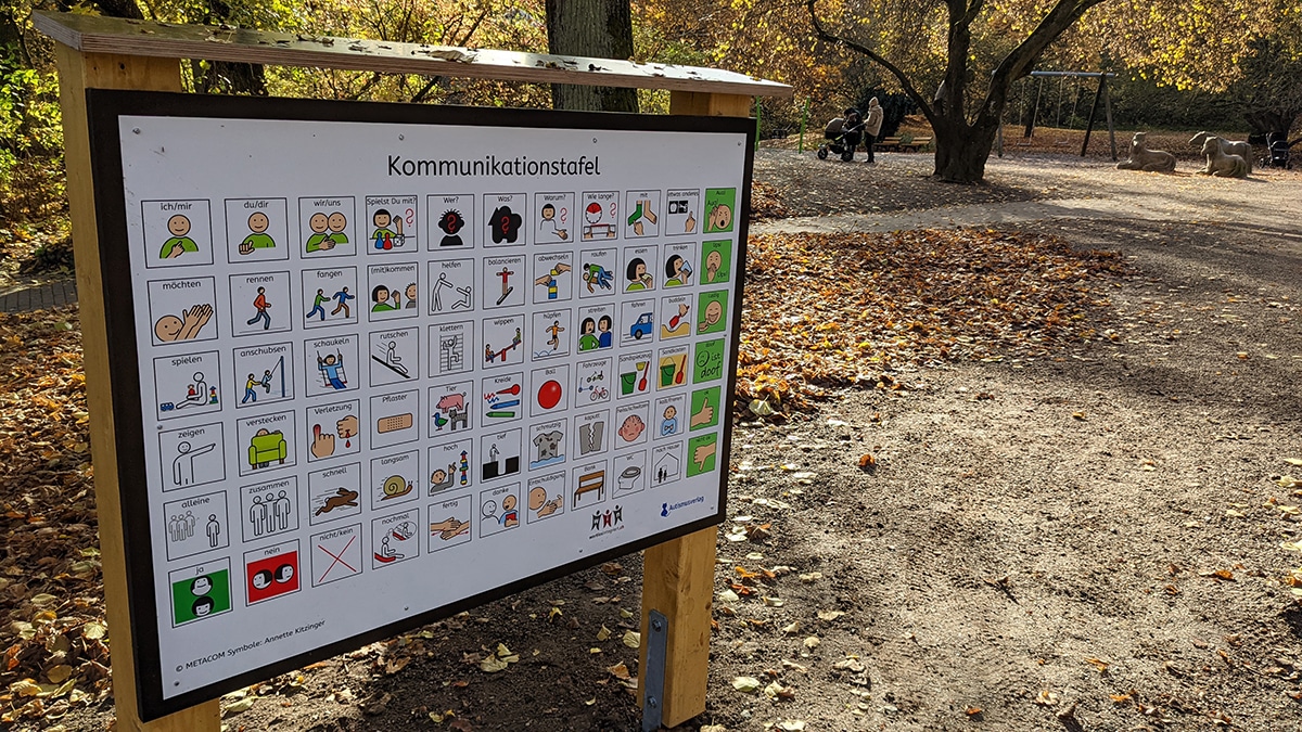 In der linken Bildhälfte steht die Tafel, rechts im Hintergrund ist der Spielplatz zu erkennen