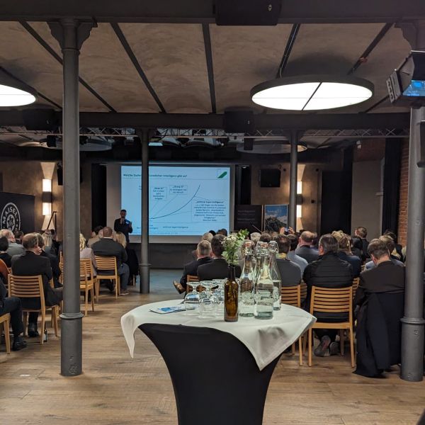 Blick in den Brausaal, Gäste des Wirtschaftsempfangs (von hinten, sitzend), Prof. Dr.-Ing. Niklas Kühl von der Universität Bayreuth präsentiert.