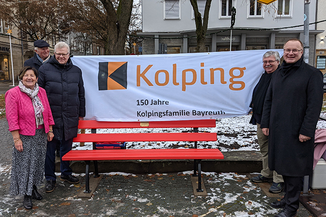Wolfram Münch, Vorstandsvorsitzender der Sparkasse Bayreuth, Stadtgartenamtsleiter Robert Pfeifer, Oberbürgermeister Thomas Ebersberger, und Maria Anna Link, Vorstand der Kolpingsfamilie Bayreuth (von rechts), mit ihrem Ehemann Manfred stehen um die rote Bank herum.