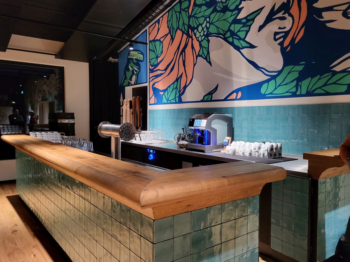 Kaffeebar mit Schankanlage, Tresen blau gekachelt mit Holz, dahinter großflächiges abstraktes Bild