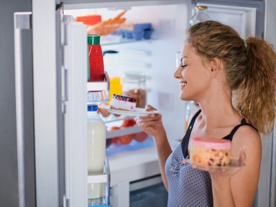 Eine junge Frau blickt in einen Kühlschrank