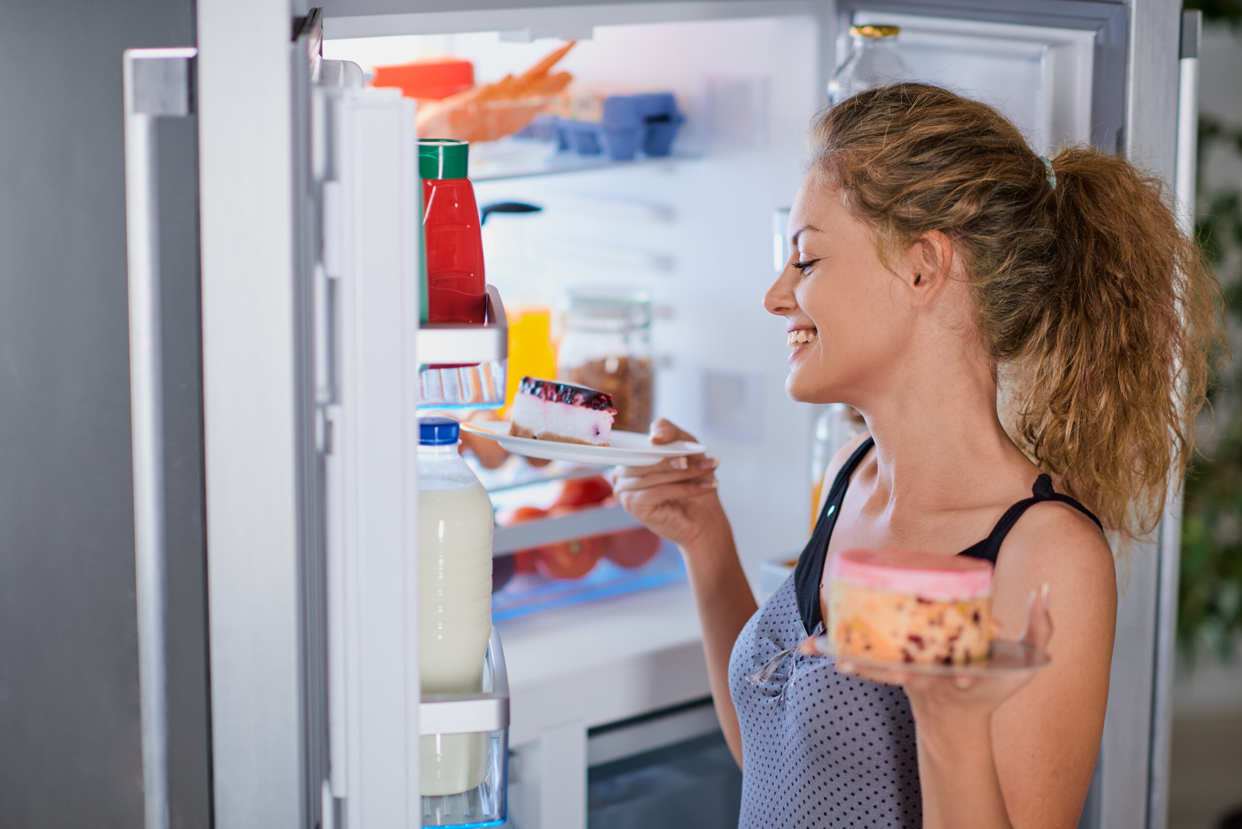 Eine junge Frau blickt in einen Kühlschrank