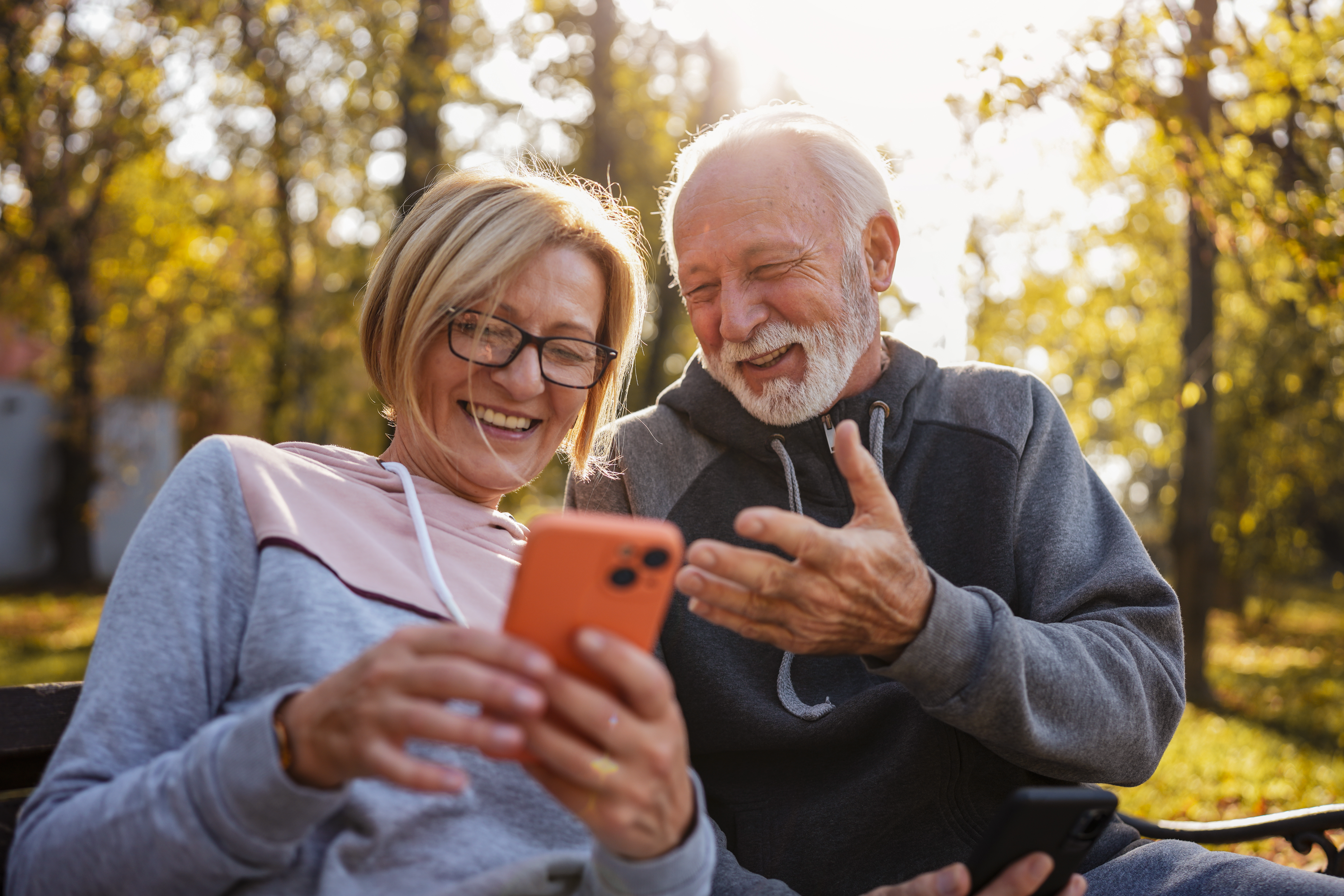 Eine ältere Frau und ein älterer Mann blicken auf ein Smartphone.