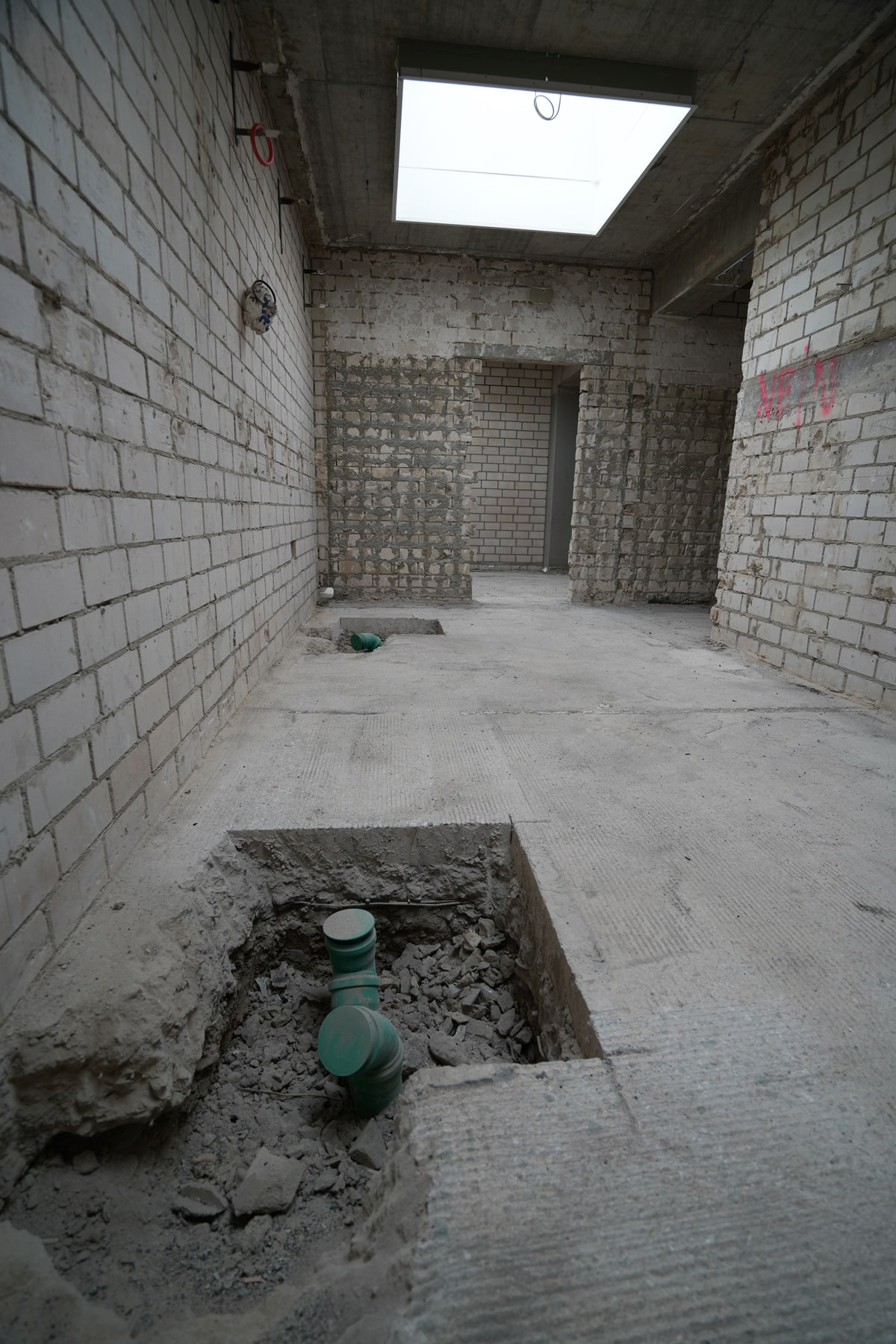 Innenbaustelle, aus deren Boden Abwasserrohre herausragen.