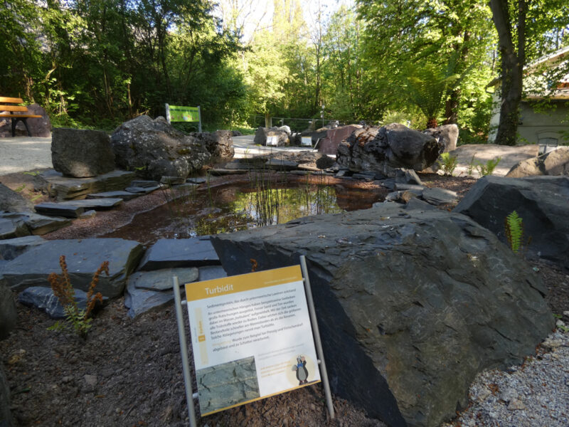 Ein Hinweistafel steht vor einem Stein