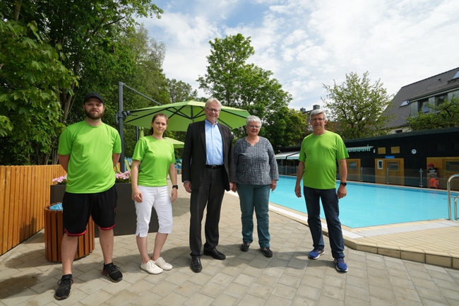 Zwei Frauen und drei Männer stehen vor einem Swimmingpool