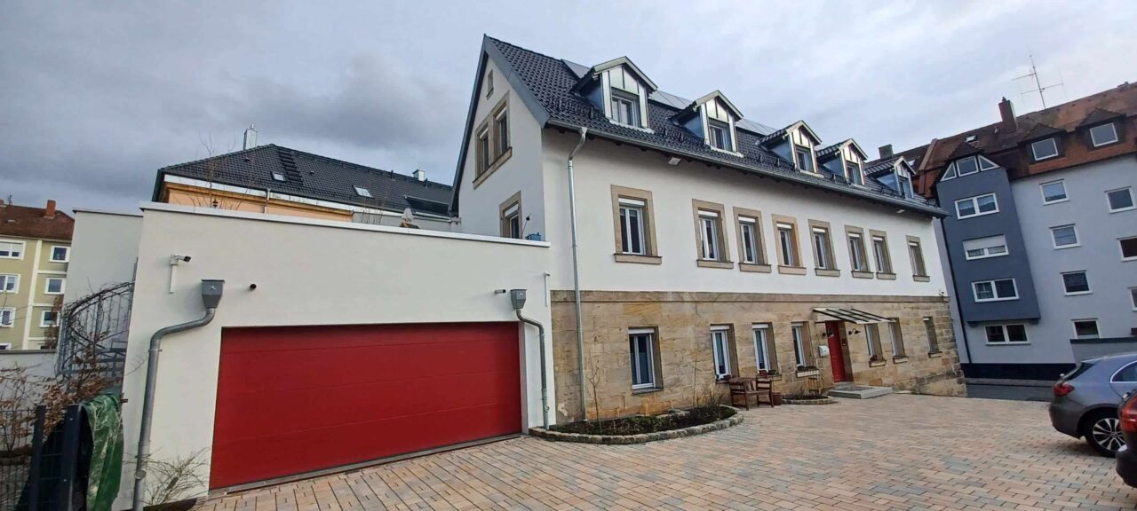 Ein Gebäudekomplex mit Garage, Sandsteinhaus und einem weiteren Mehrfamilienhaus