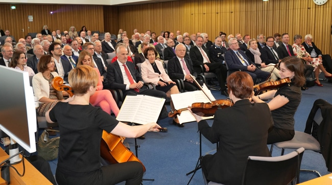 Eine große Gruppe von Frauen und Männern lauscht einer Gruppe von Musikern