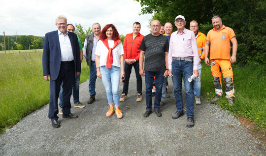Eine Gruppe von Menschen steht auf einem Wirtschaftsweg