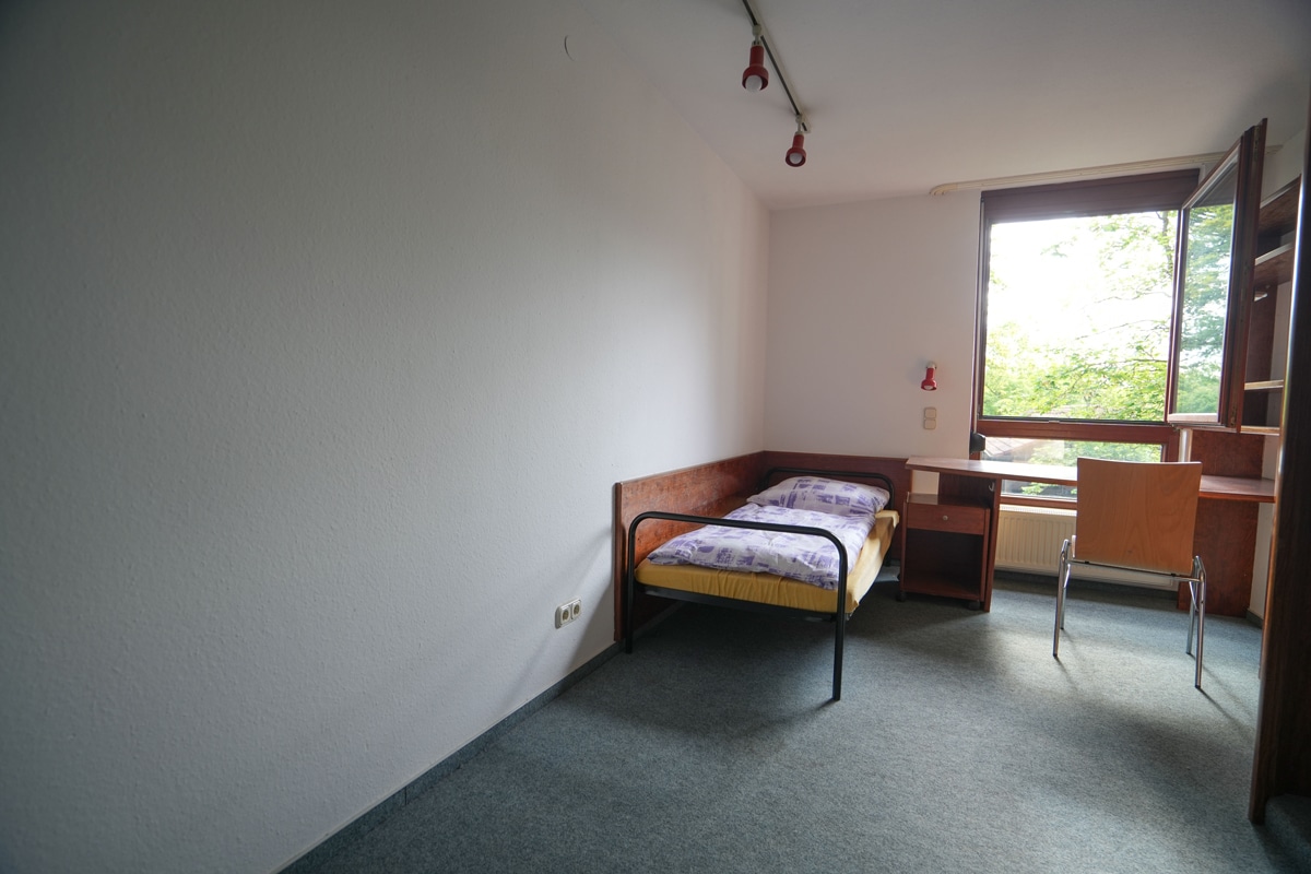 Ein Zimmer mit Bett, Schreibtisch und Tisch.