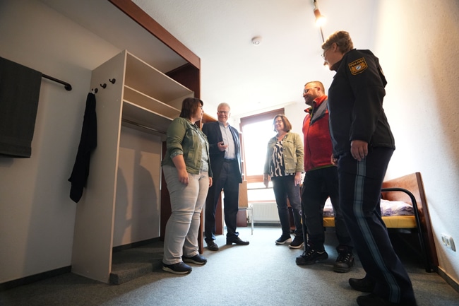 Mehrere Personen stehen in einem unbewohnten Raum.