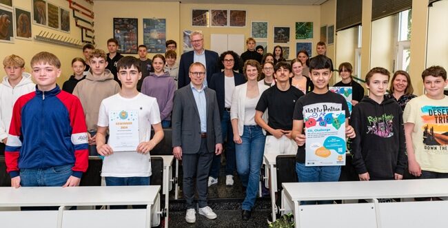 Schülerinnen und Schüler der 8c des Graf-Münster-Gymnasiums und ihre Lehrerin Tabea Tchokothe (2. Reihe re.) lassen sich für ihren Gewinn der CO2-Schulchallenge der Europäischen Metropolregion Nürnberg in der Kategorie „Kreativstes und innovativstes Portfolio“ feiern. Es gratulierten (im Mittelgang von hinten): Oberbürgermeister Thomas Ebersberger, Schulpflegerin Luisa Barjak-Funke, Klimaschutzmanagerin Gesa Thomas und Schuldirektor Christian Kramer.