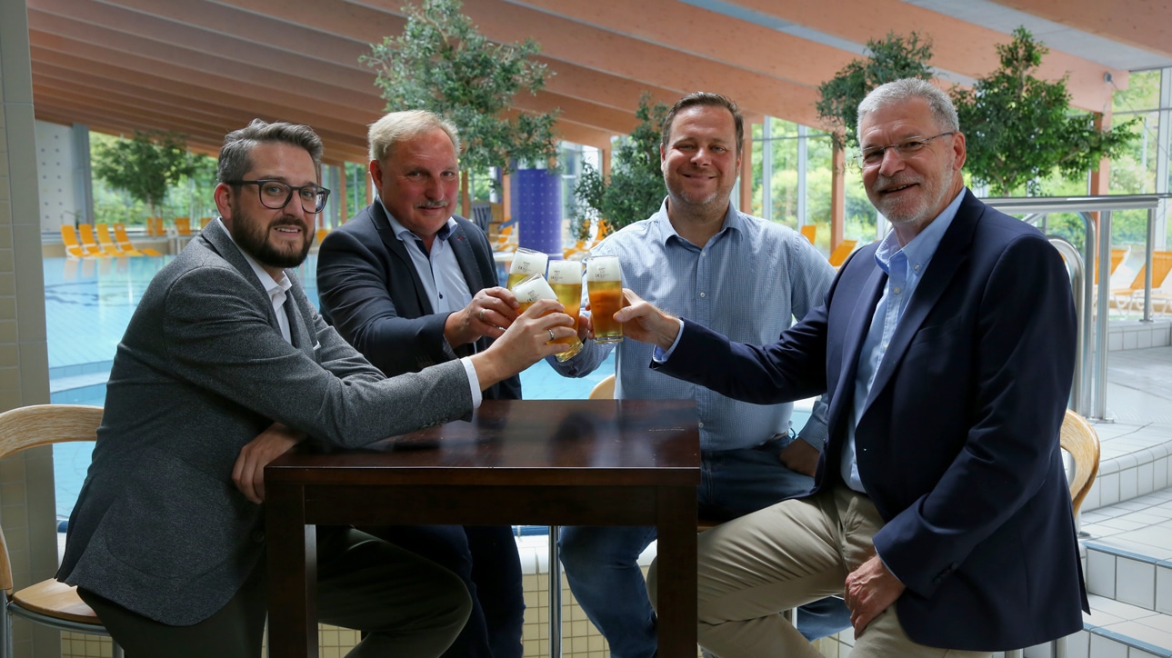 Vier Männer sitzen an einem Bistro-Tisch und prosten sich zu. | Foto: Stadtwerke Bayreuth