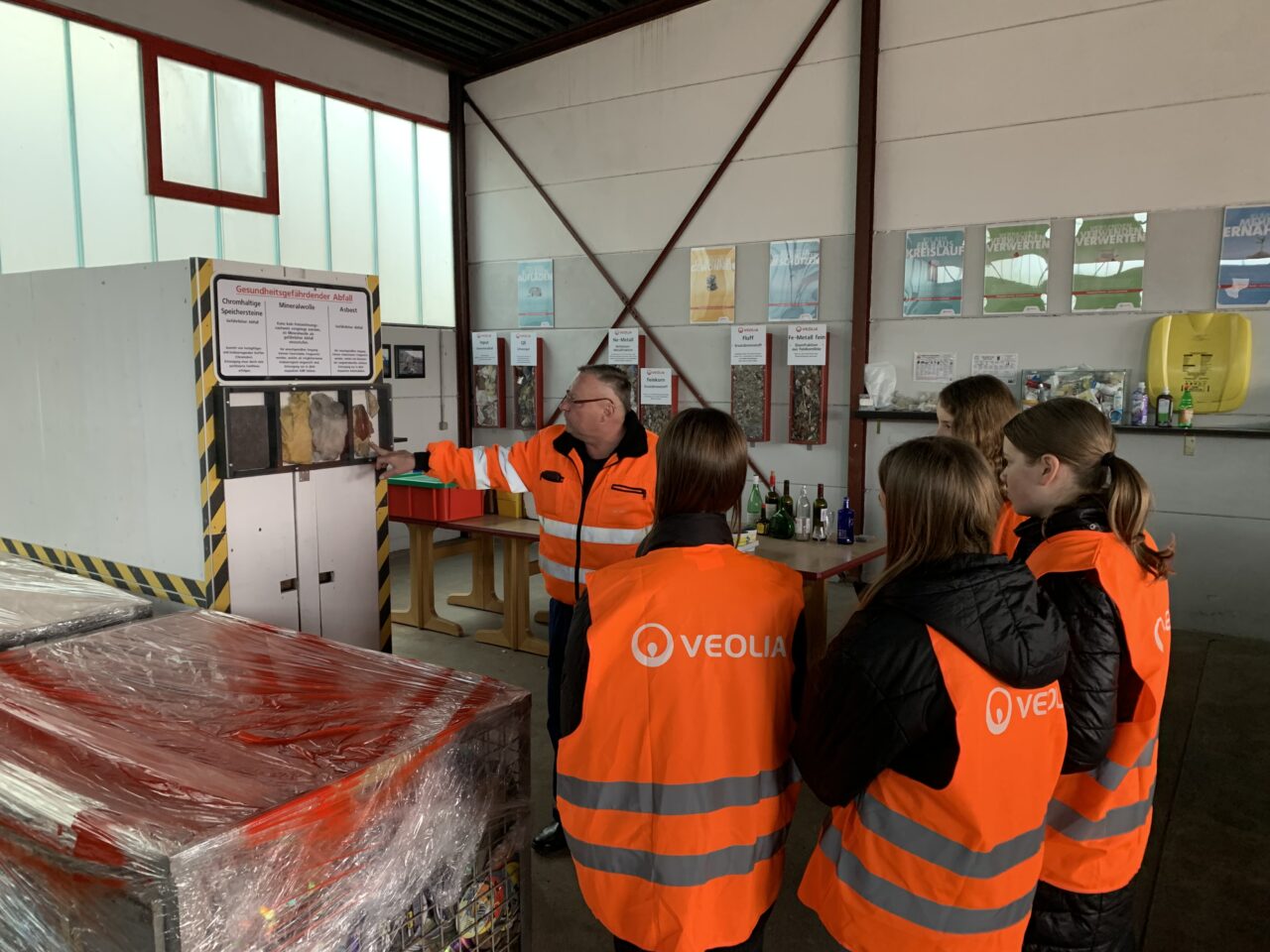 Jugendliche auf dem Wertstoffhof der Firma Veolia - alle in orangen Warnwesten