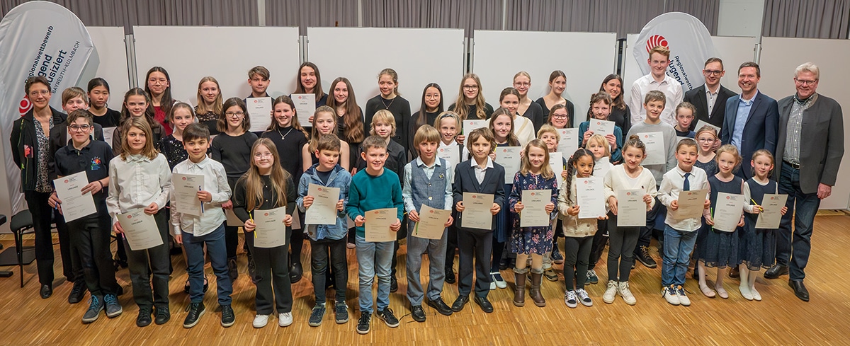 Die Preisträger/innen stehen nebeneinander und halten ihre Urkunden in der Hand.