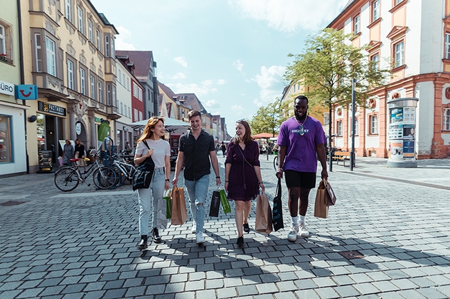 4 Leute schlendern mit Einkaufstüten durch die Innenstadt