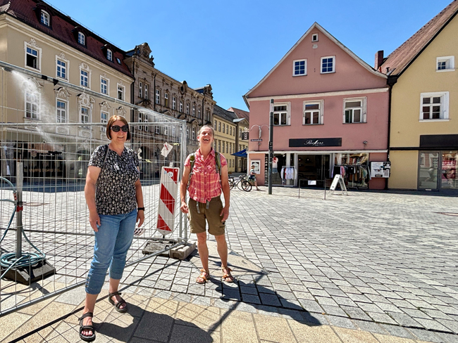 Die Stadt Bayreuth hat in der Fußgängerzone unter anderem beim Caffé Rossi und hier beim Ehrenhof Sprühnebelschläuche zur Abkühlung aufstellen lassen, sehr zur Freude unter anderem dieser beiden Passantinnen. Foto: Stadt Bayreuth