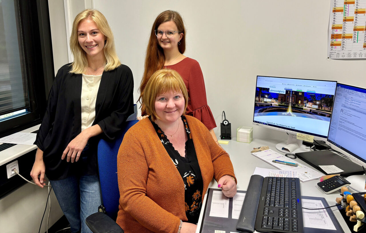 Drei Frauen stehen an einem Schreibtisch mit Computer. | Foto: Stadt Bayreuth