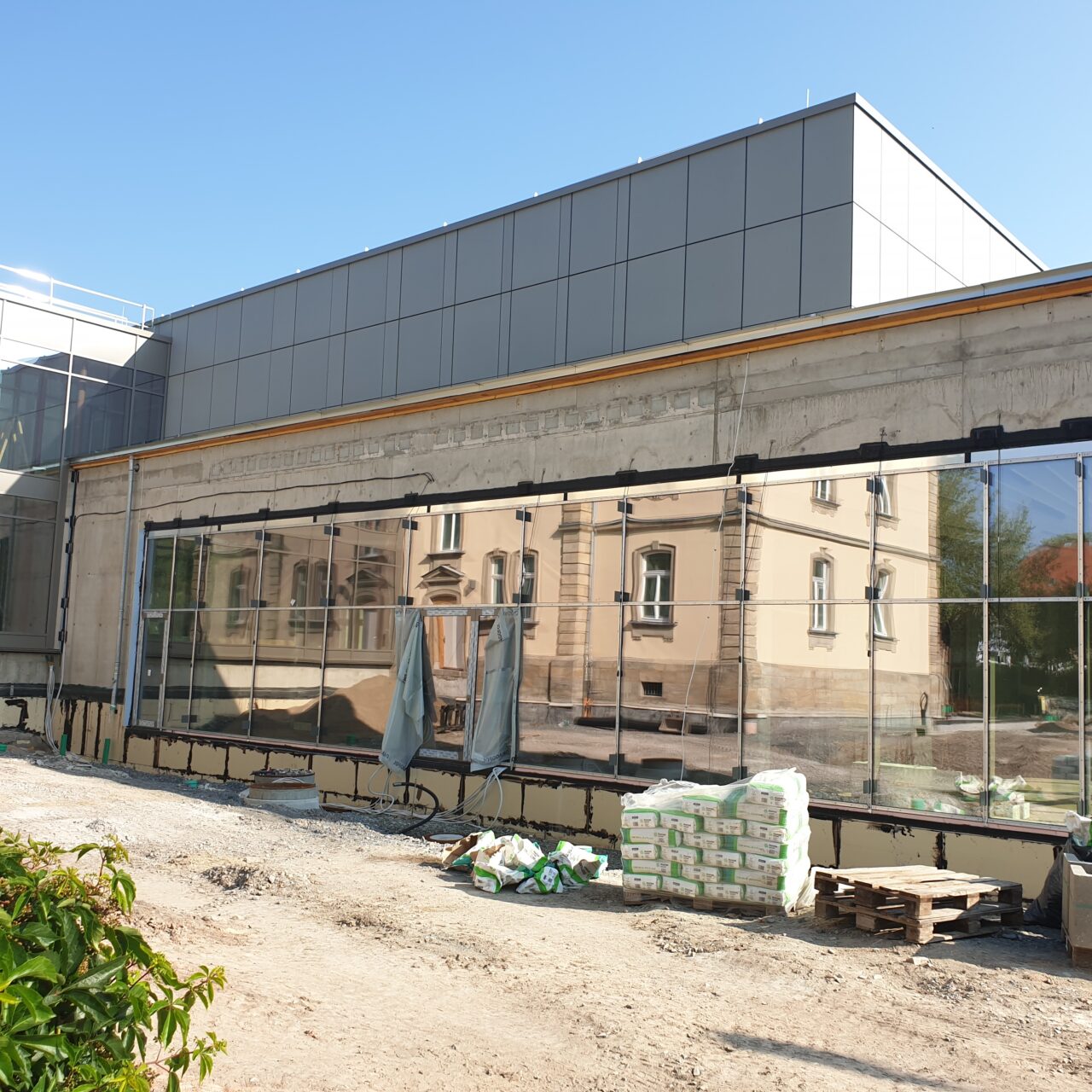 Blick auf den öffentlichen Bereich des Neubaus (Baustelle). Die Villa spiegelt sich.