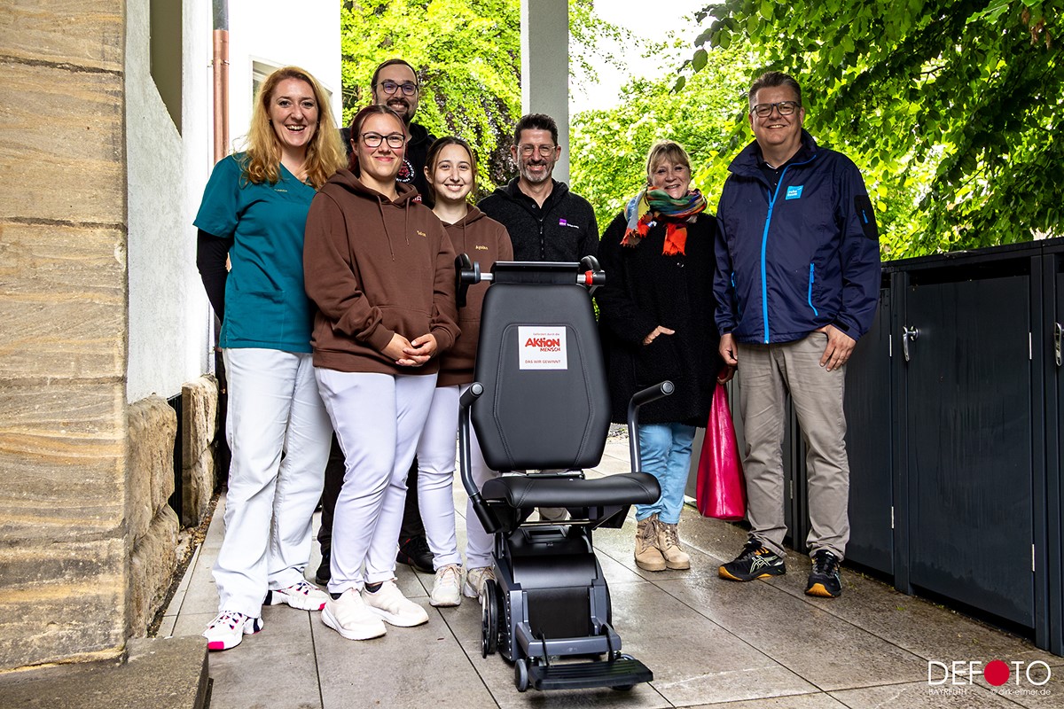 Mehrere Personen stehen vor dem Treppensteiger vom Reha-Team Nordbayern