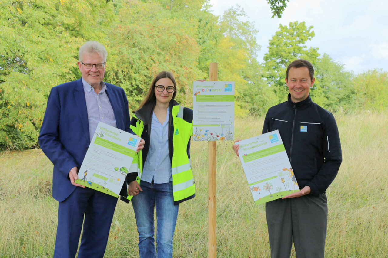 Drei Personen stehen auf einer bunten Wiese und halten Schilder in den Händen. | Foto: Stadtwerke Bayreuth
