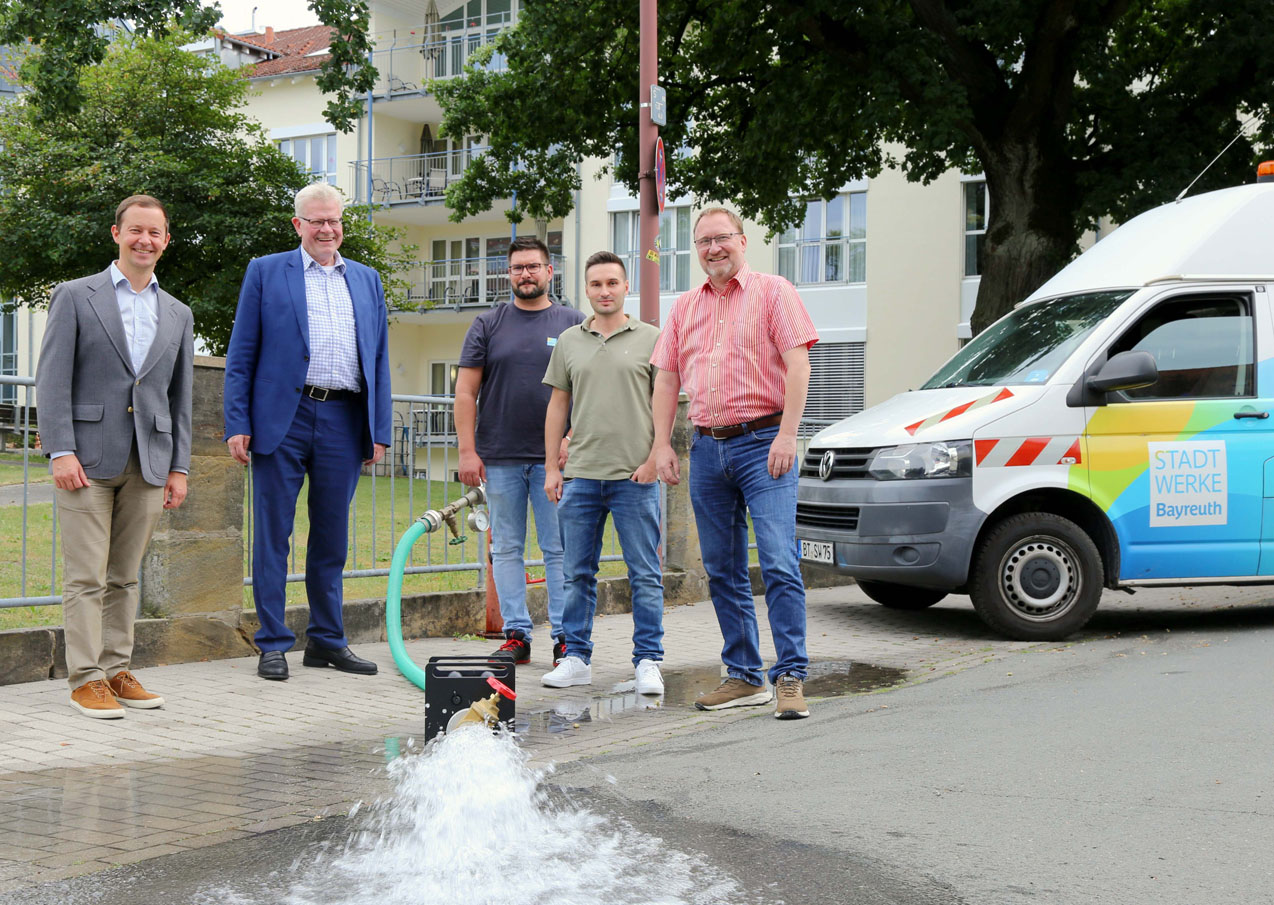Fünf Männer stehen an einem laufenden Wasserhydranten. | Foto: Stadtwerke Bayreuth