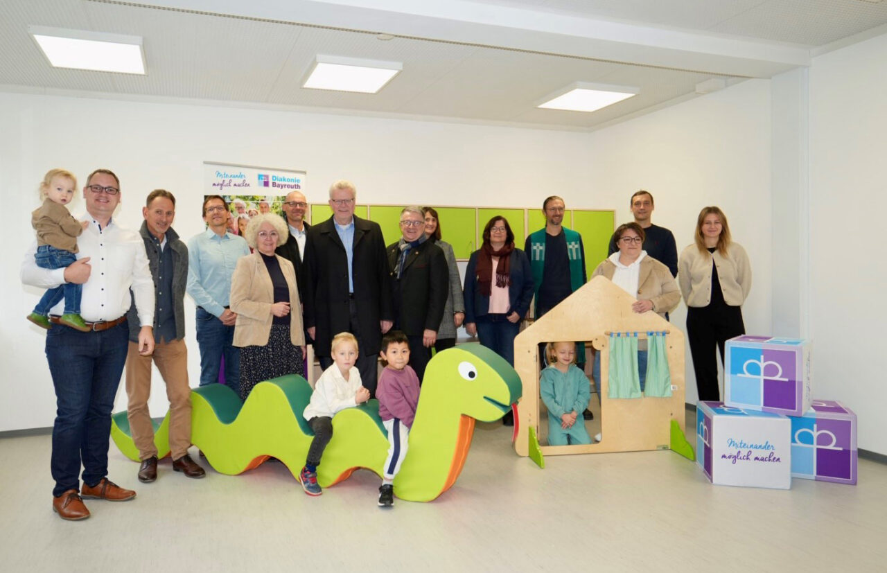 Eine Gruppe von Personen steht in einem Kindergartenzimmer. Im Vordergrund ein großes grünes Spielgerät. | Foto: Stadt Bayreuth