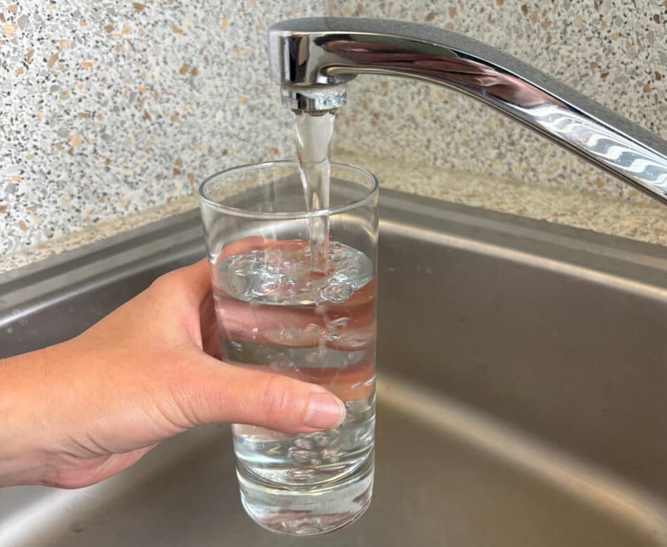 Glas Wasser unter einem Wasserhahn.