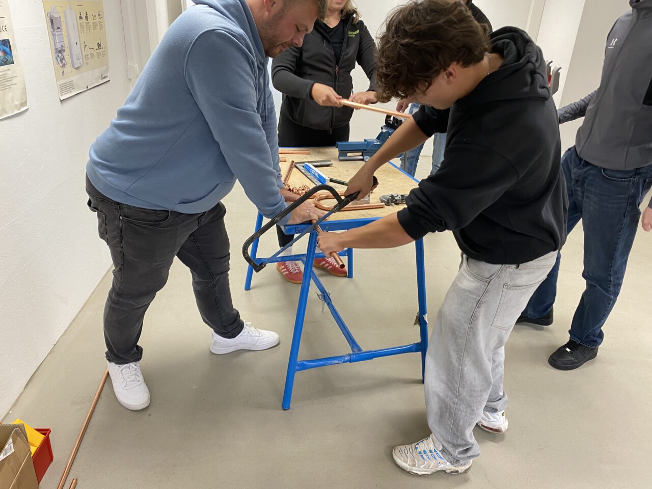 Zwei Personen sägen an einem Metallrohr