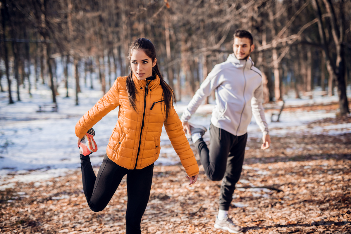 Zwei Personen treiben Sport im winterlichen Wald. Foto: Adobe Stock