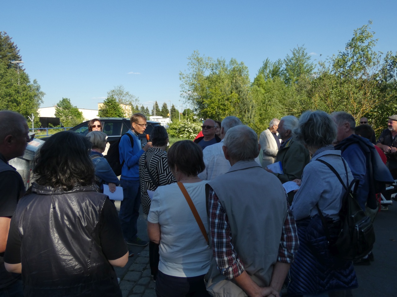 Bürger stehen zusammen auf der Straße in St. Georgen/ Insel und hören einen Vortrag zur Stadtentwicklung vom Leiter des Stadtplanungsamtes Herrn Meyer zu Helligen.
